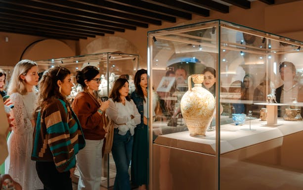 Visitors observing ornate pottery at Abu Dhabi Royal Equestrian Arts exhibit.