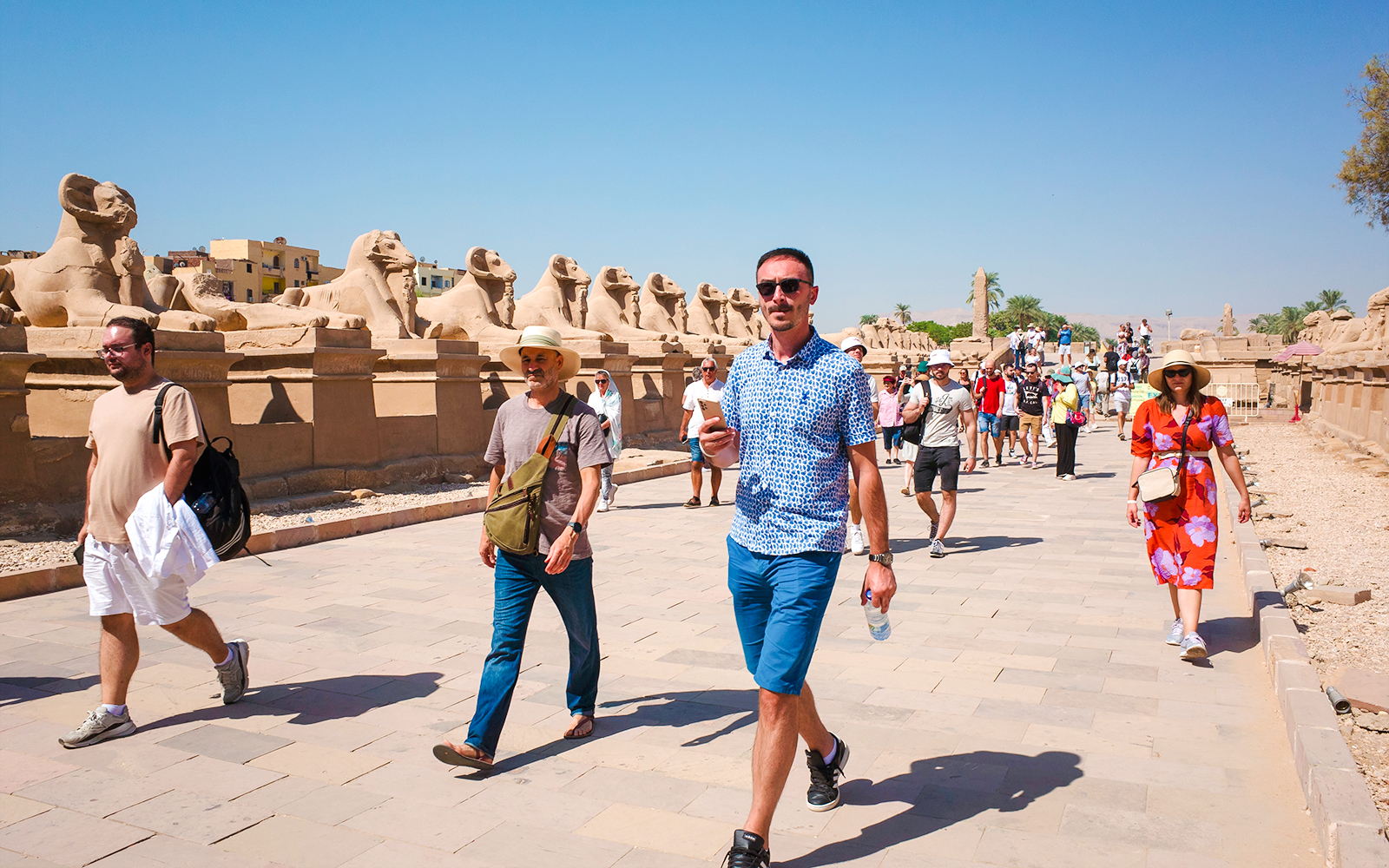 Tourists walking along the Avenue of Sphinxes at Luxor Temple, Egypt.