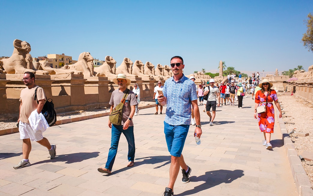 Tourists walking along the Avenue of Sphinxes at Luxor Temple, Egypt.