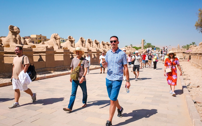 Tourists walking along the Avenue of Sphinxes at Luxor Temple, Egypt.