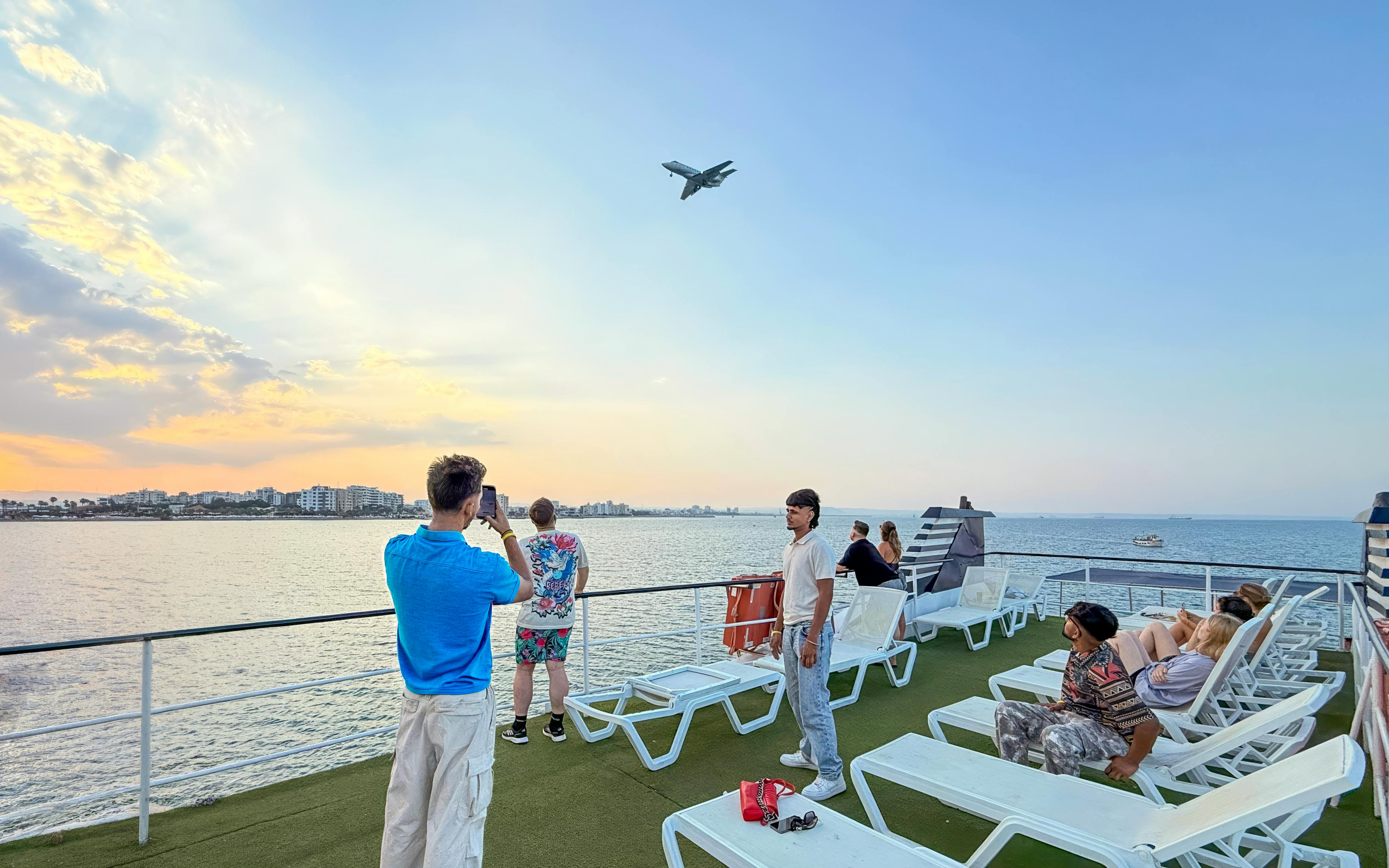 Sunset cruise from Larnaca with people on deck watching a plane fly overhead.