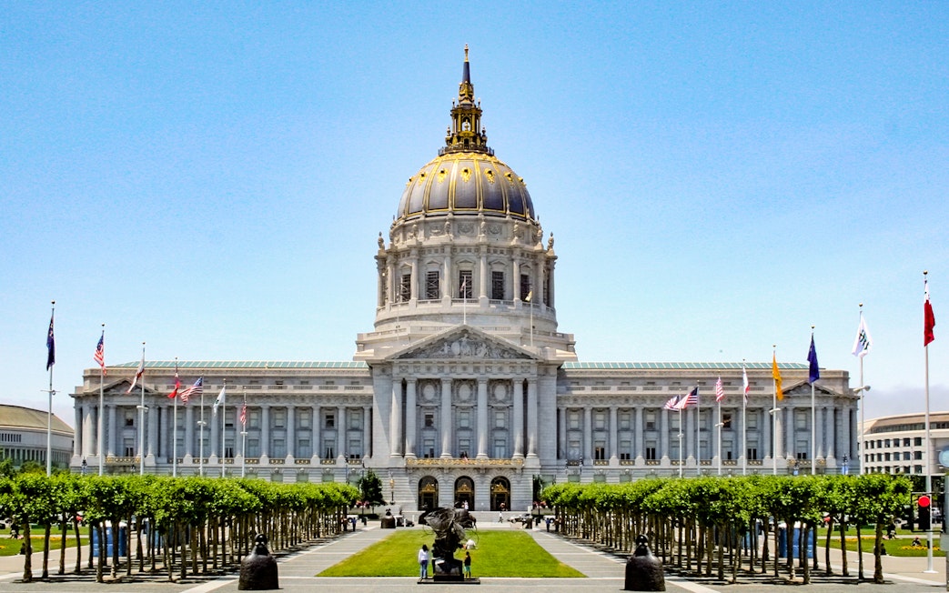 San Francisco City Hall with flags and trees in Civic Center, California.
