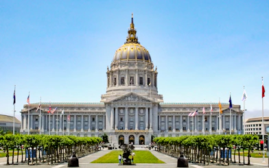 San Francisco City Hall with flags and trees in Civic Center, California.
