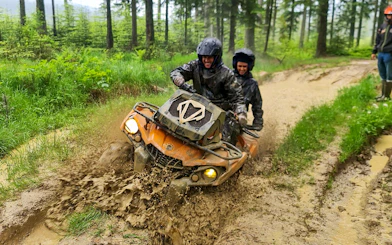 Visitors riding a quad bike through muddy forest trail in Zakopane.