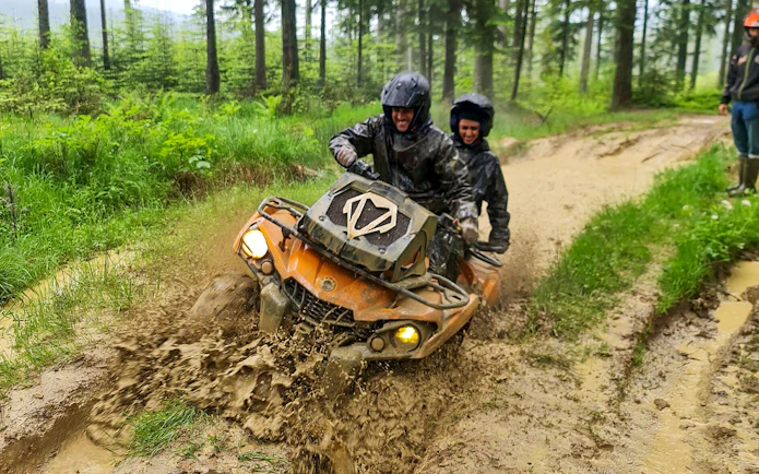 Visitors riding a quad bike through muddy forest trail in Zakopane.