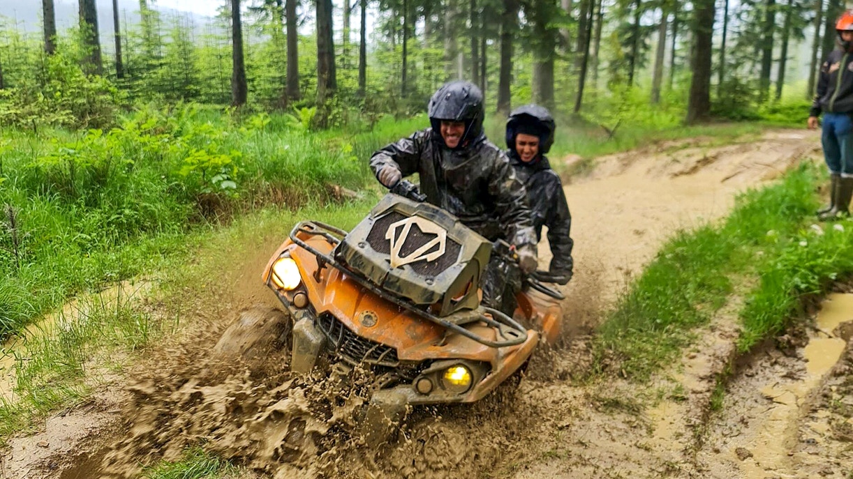 Visitors riding a quad bike through muddy forest trail in Zakopane.