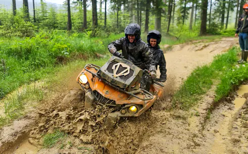 Visitors riding a quad bike through muddy forest trail in Zakopane.