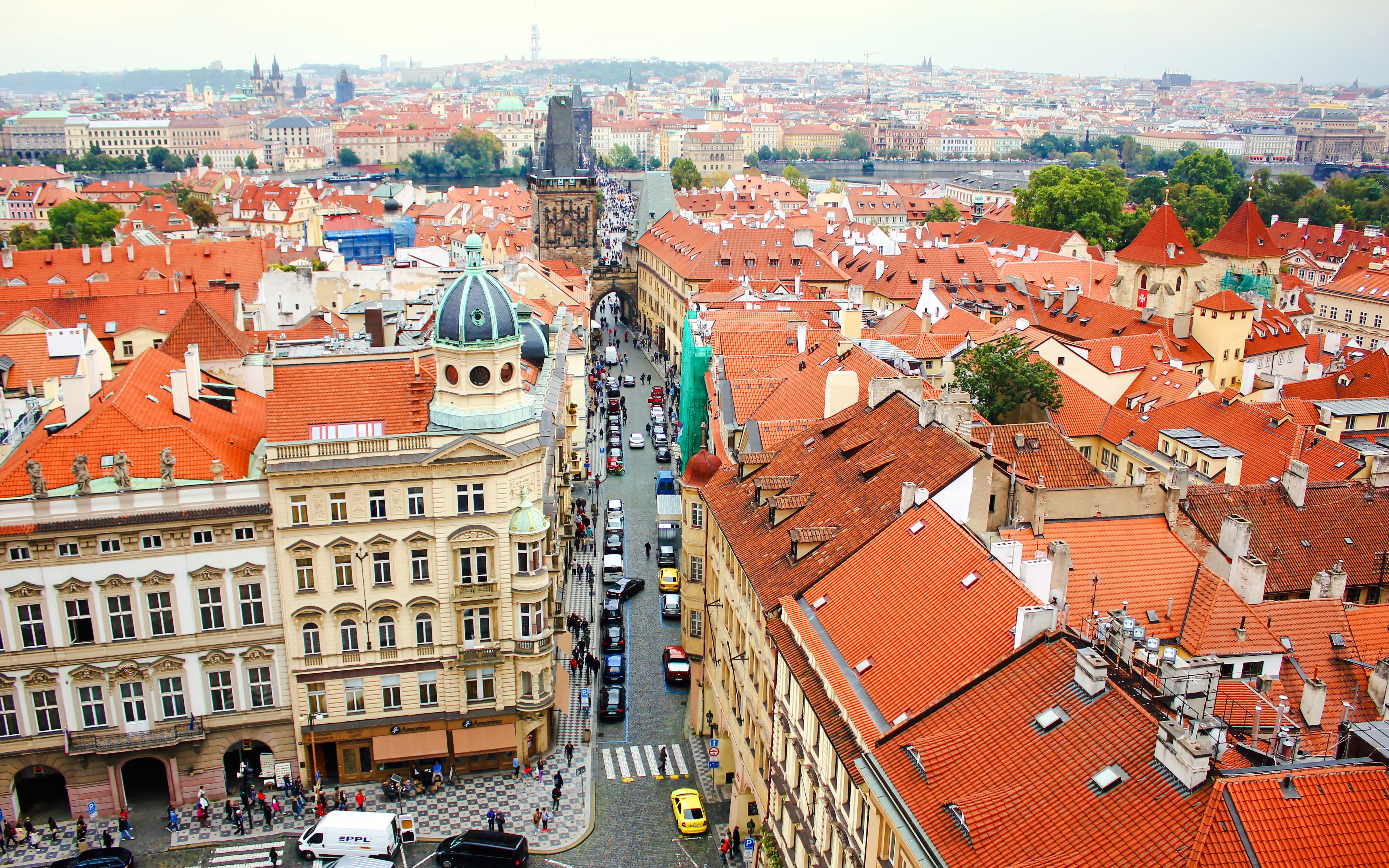 Aerial view of Mostecka street near St Nicholas Bell Tower, Prague, with red rooftops and cobblestone path.