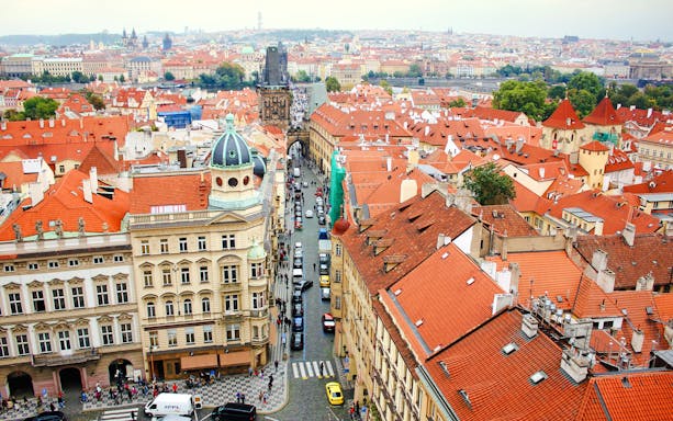 Aerial view of Mostecka street near St Nicholas Bell Tower, Prague, with red rooftops and cobblestone path.