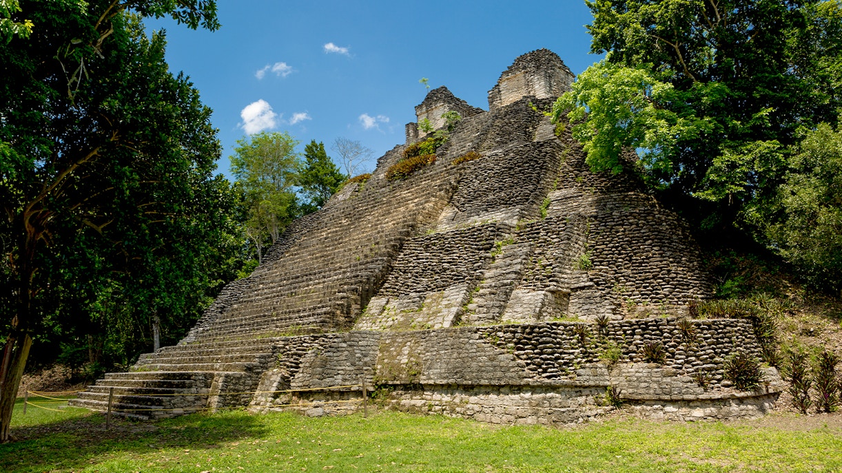 Stone pyramid structure surrounded by lush greenery at Temple of the Owls near Chichen Itza.