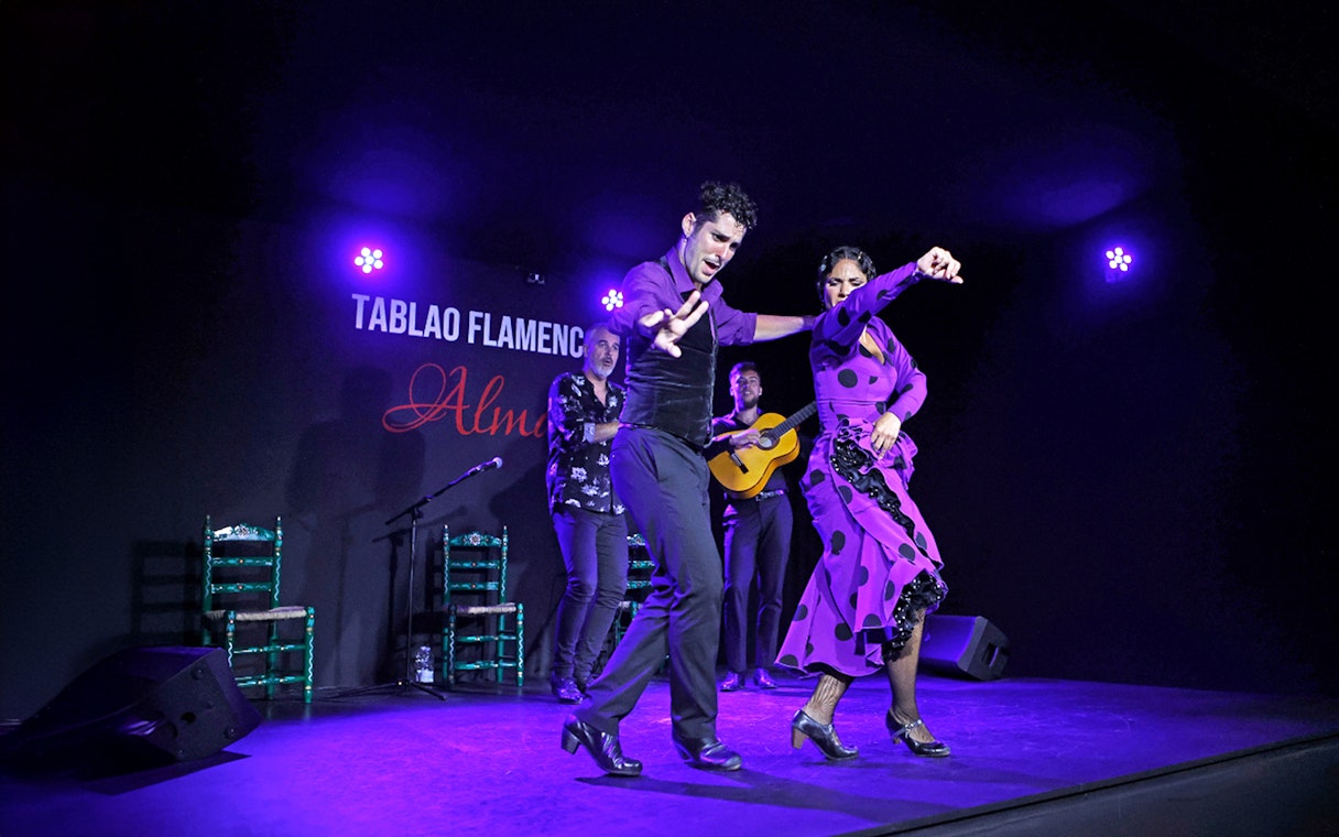 Flamenco dancers performing at Tablao Flamenco Alma with musicians in the background.