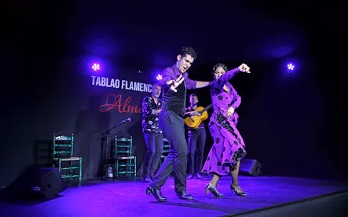 Flamenco dancers performing at Tablao Flamenco Alma with musicians in the background.