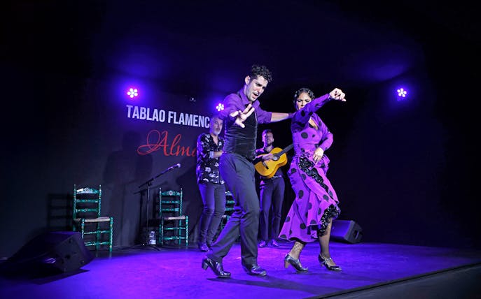 Flamenco dancers performing at Tablao Flamenco Alma with musicians in the background.
