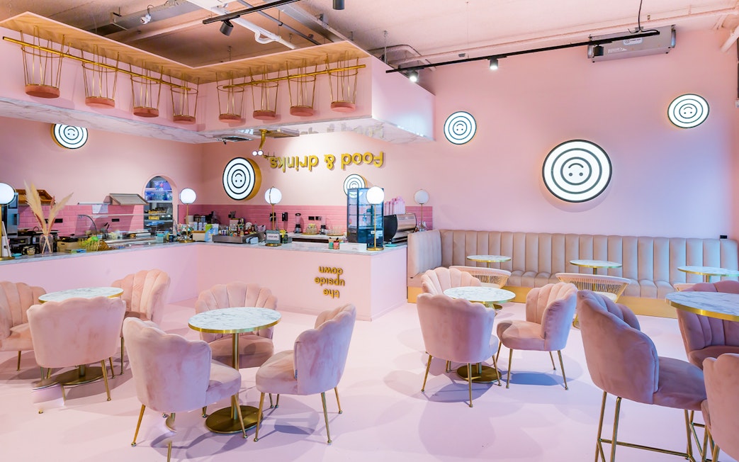 Upside Down Amsterdam cafe interior with pink decor and circular tables.