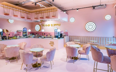Upside Down Amsterdam cafe interior with pink decor and circular tables.