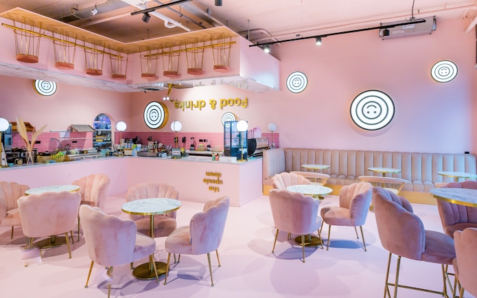 Upside Down Amsterdam cafe interior with pink decor and circular tables.