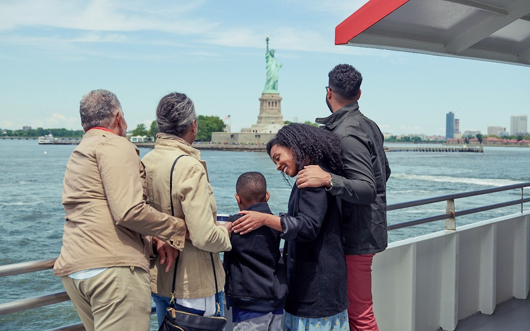Family on Circle Line ferry viewing Statue of Liberty, New York City.