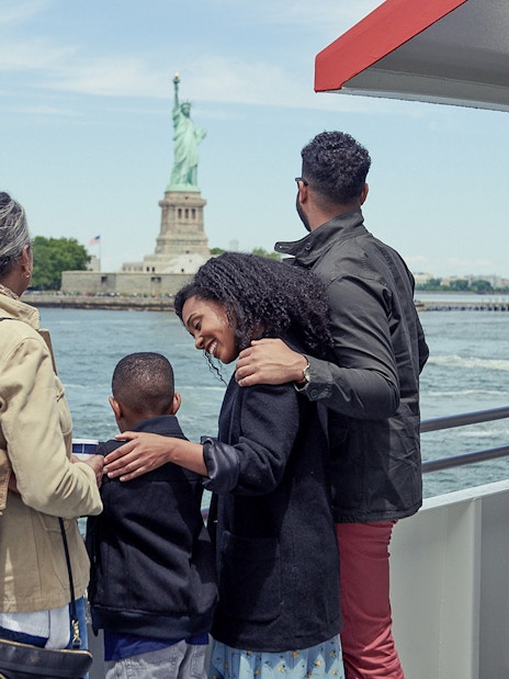 Family on Circle Line ferry viewing Statue of Liberty, New York City.