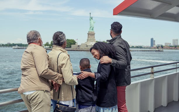 Family on Circle Line ferry viewing Statue of Liberty, New York City.