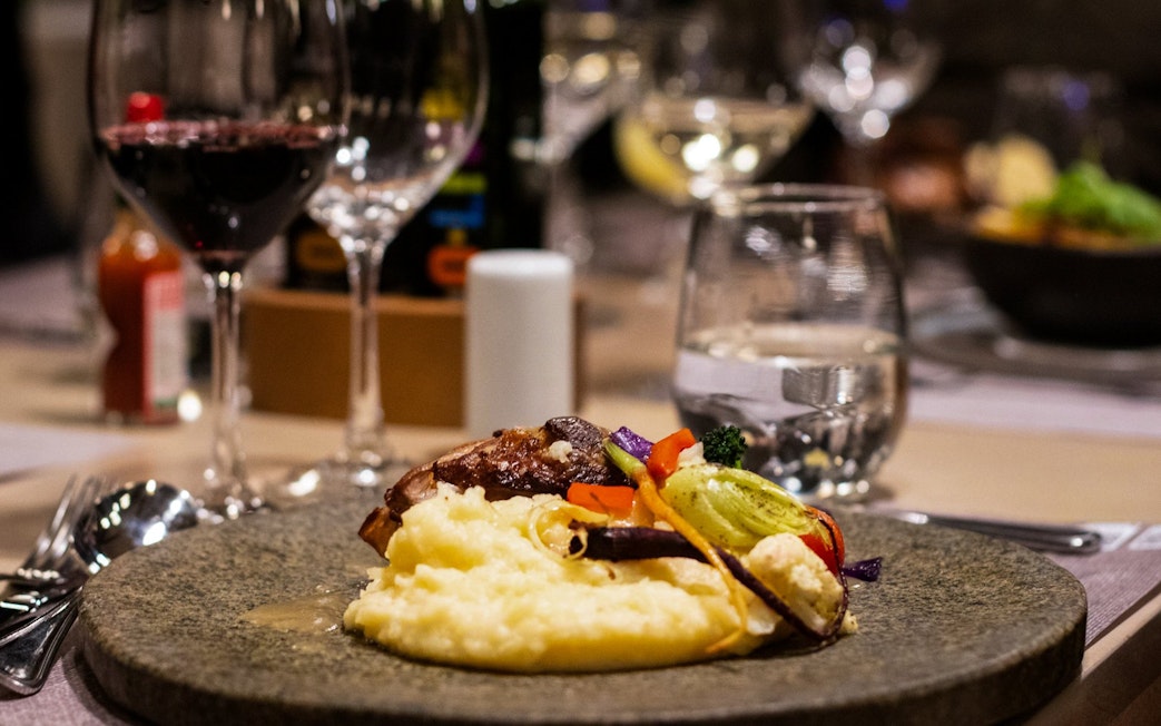 Dinner plate with mashed potatoes, vegetables, and wine at Viña Concha y Toro Nighttime Dinner Show.