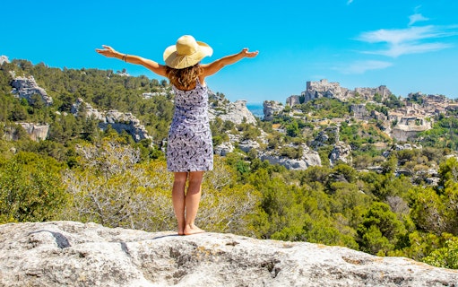 Person enjoying panoramic view of Les Baux-de-Provence village and surrounding landscape.