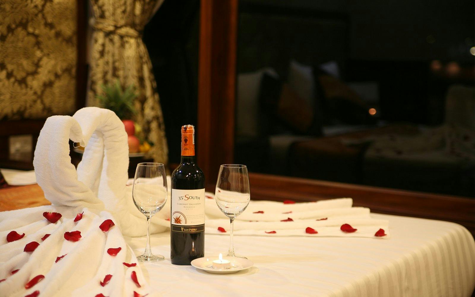 Towel swans and wine on a bed with rose petals, Halong Bay 3 Star Cruise.