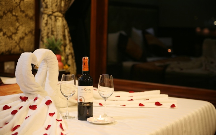 Towel swans and wine on a bed with rose petals, Halong Bay 3 Star Cruise.