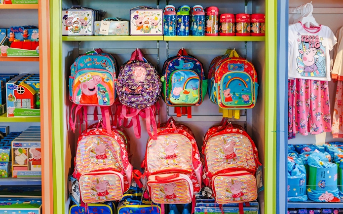 Peppa Pig merchandise display with backpacks and clothing at Peppa Pig Theme Park, Florida.