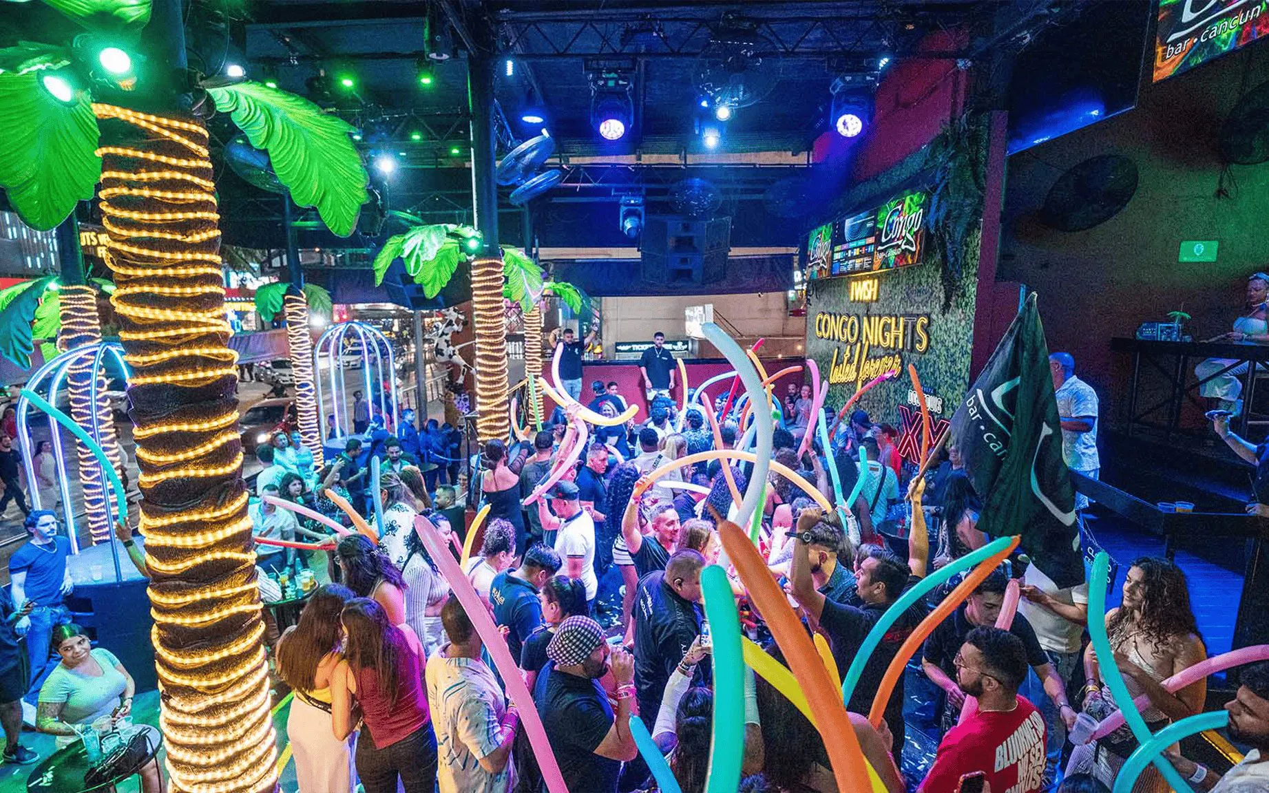 Crowd enjoying vibrant nightlife at Coco Bongo Congo Bar with colorful lights and decorations.