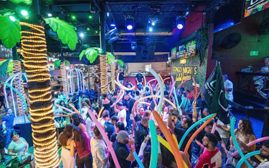 Crowd enjoying vibrant nightlife at Coco Bongo Congo Bar with colorful lights and decorations.