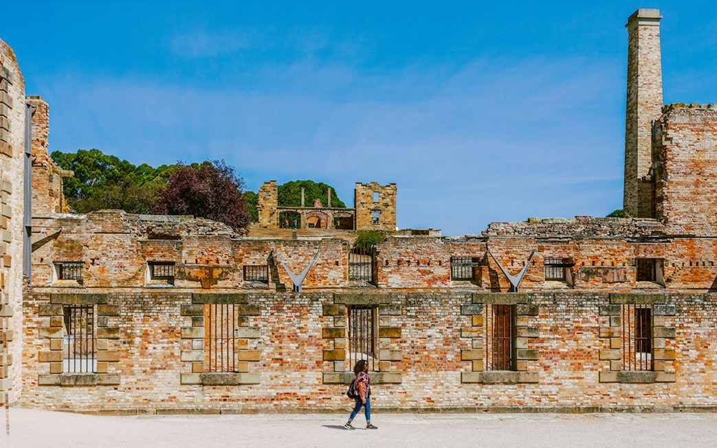 Port Arthur historic site with visitor walking along brick ruins, Tasmania.