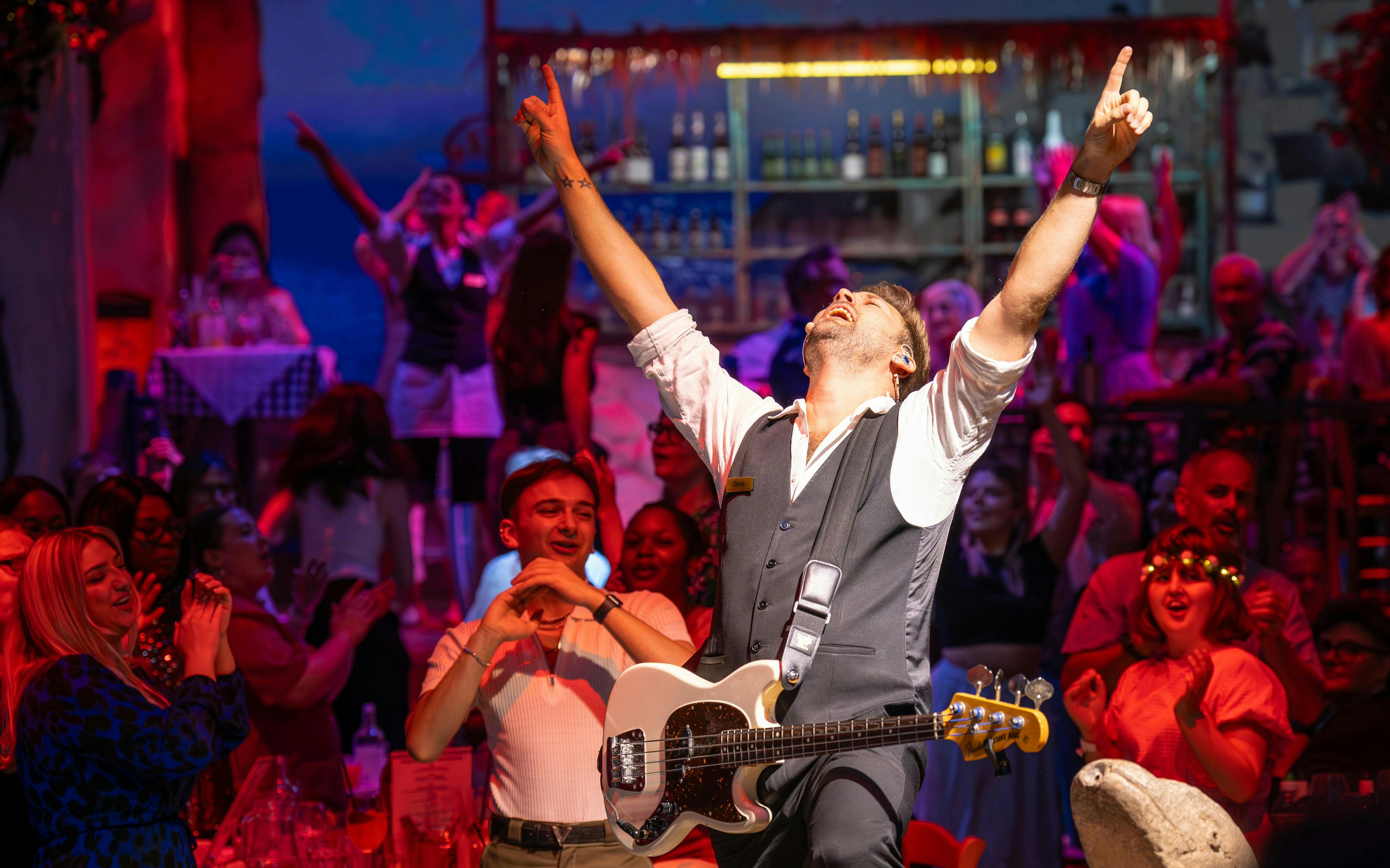 Performer with guitar engaging audience at Mamma Mia! The Party show.