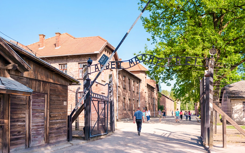 Entrance gate to Auschwitz I with visitors walking through.