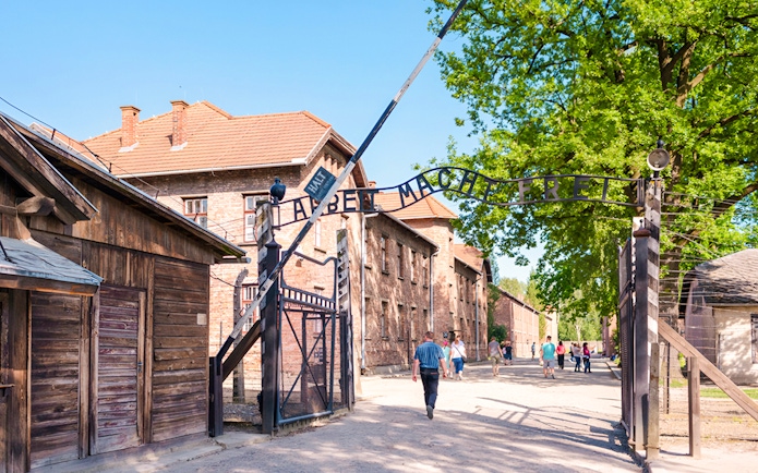 Entrance gate to Auschwitz I with visitors walking through.