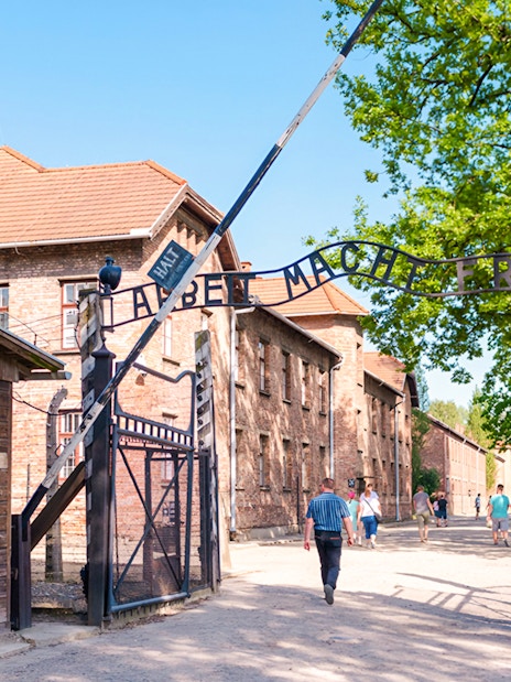 Entrance gate to Auschwitz I with visitors walking through.
