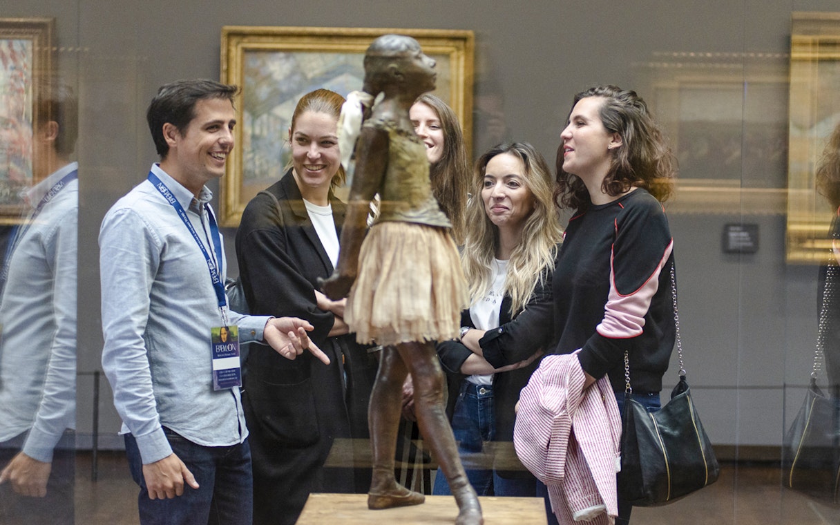 Guide with tourists viewing sculpture inside Orsay Museum, France.