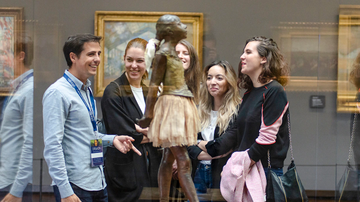 Guide with tourists viewing sculpture inside Orsay Museum, France.