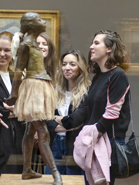 Guide with tourists viewing sculpture inside Orsay Museum, France.