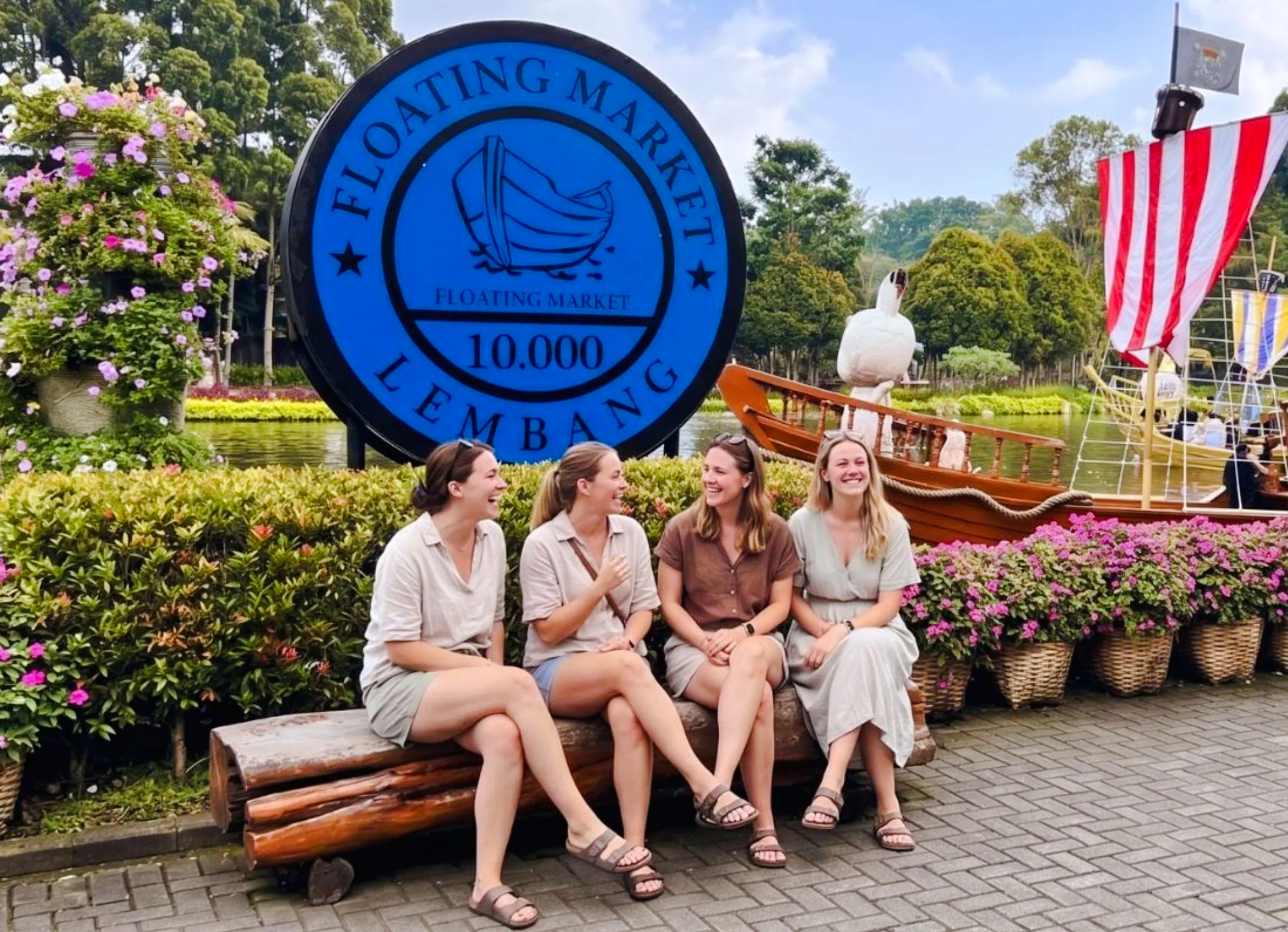 Visitors at Lembang Floating Market in Bandung, with a traditional boat and colorful flowers.