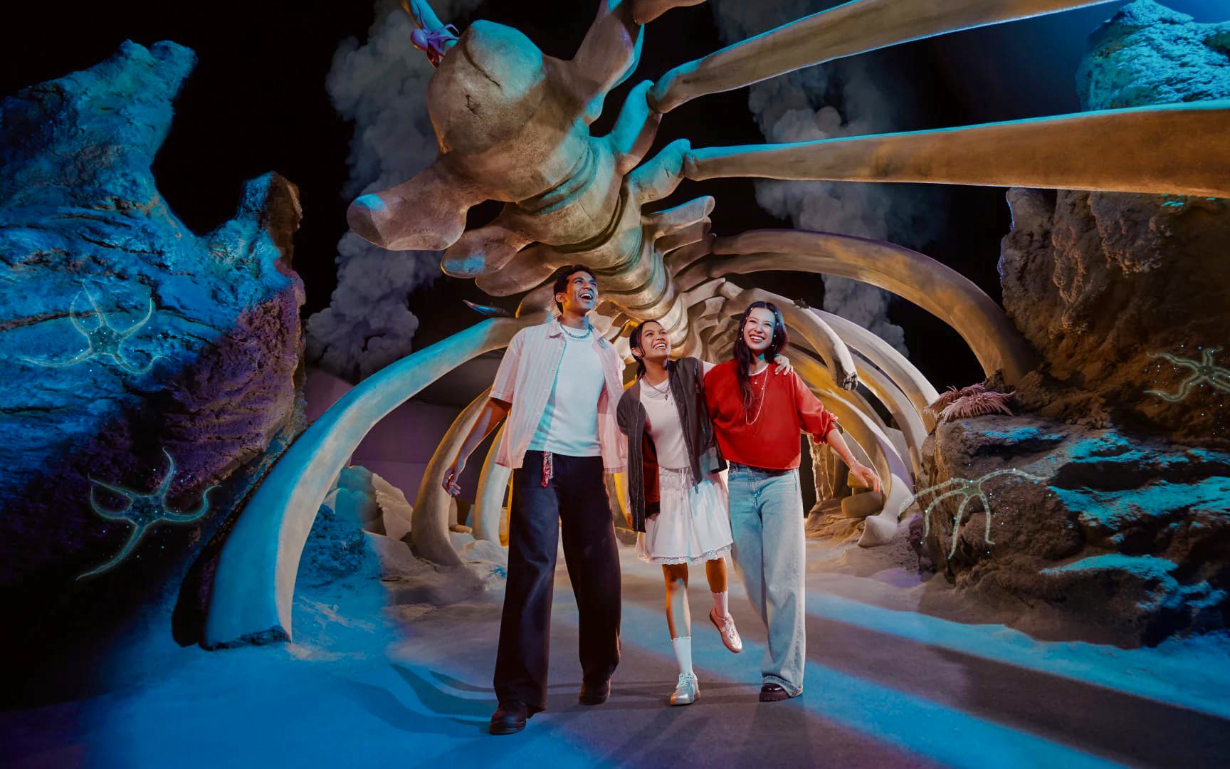 Visitors walking under a large skeleton display at SG Oceanarium, Singapore.