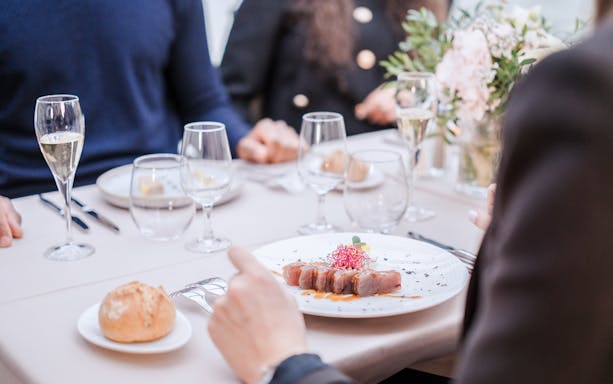 Seine River lunch cruise dining table with gourmet meal and champagne.