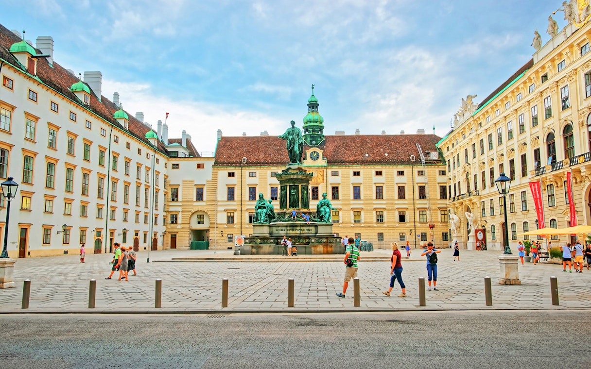 Courtyard view of Hofburg Palace complex with statue and historic buildings, Vienna.