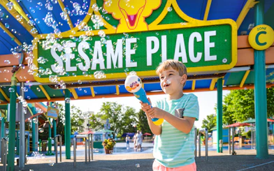Child playing with bubbles at Sesame Place Philadelphia entrance.