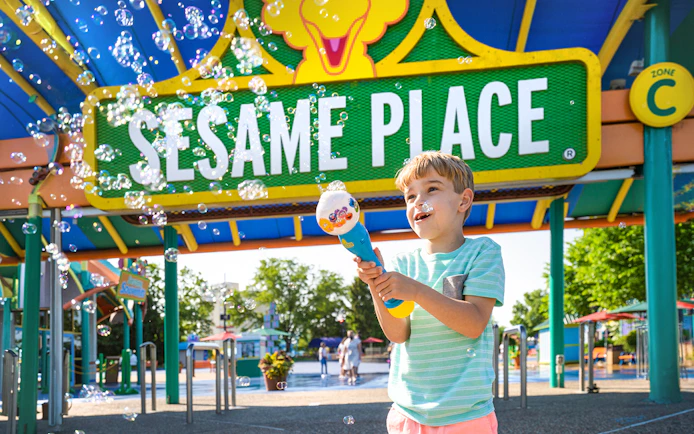 Child playing with bubbles at Sesame Place Philadelphia entrance.