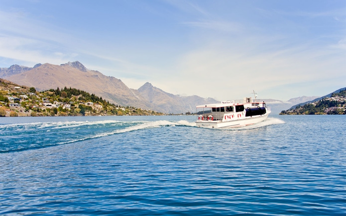 Tour boat cruising on Lake Wakatipu with Queenstown mountains in the background.