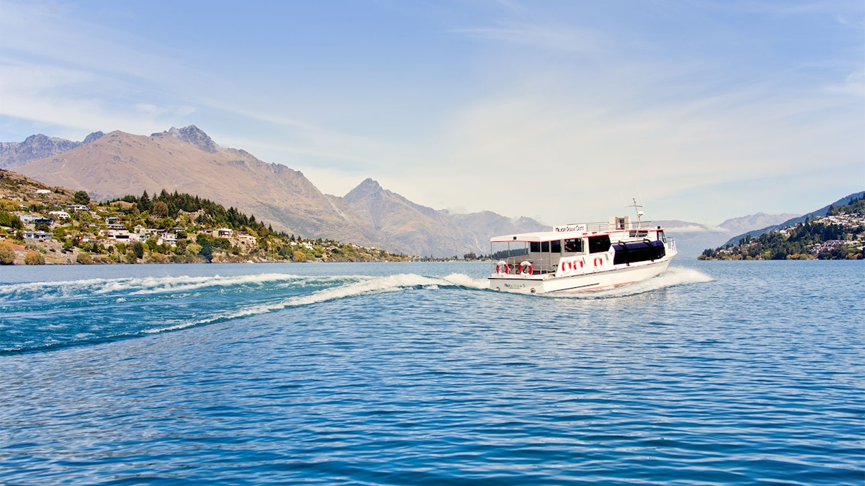 Tour boat cruising on Lake Wakatipu with Queenstown mountains in the background.
