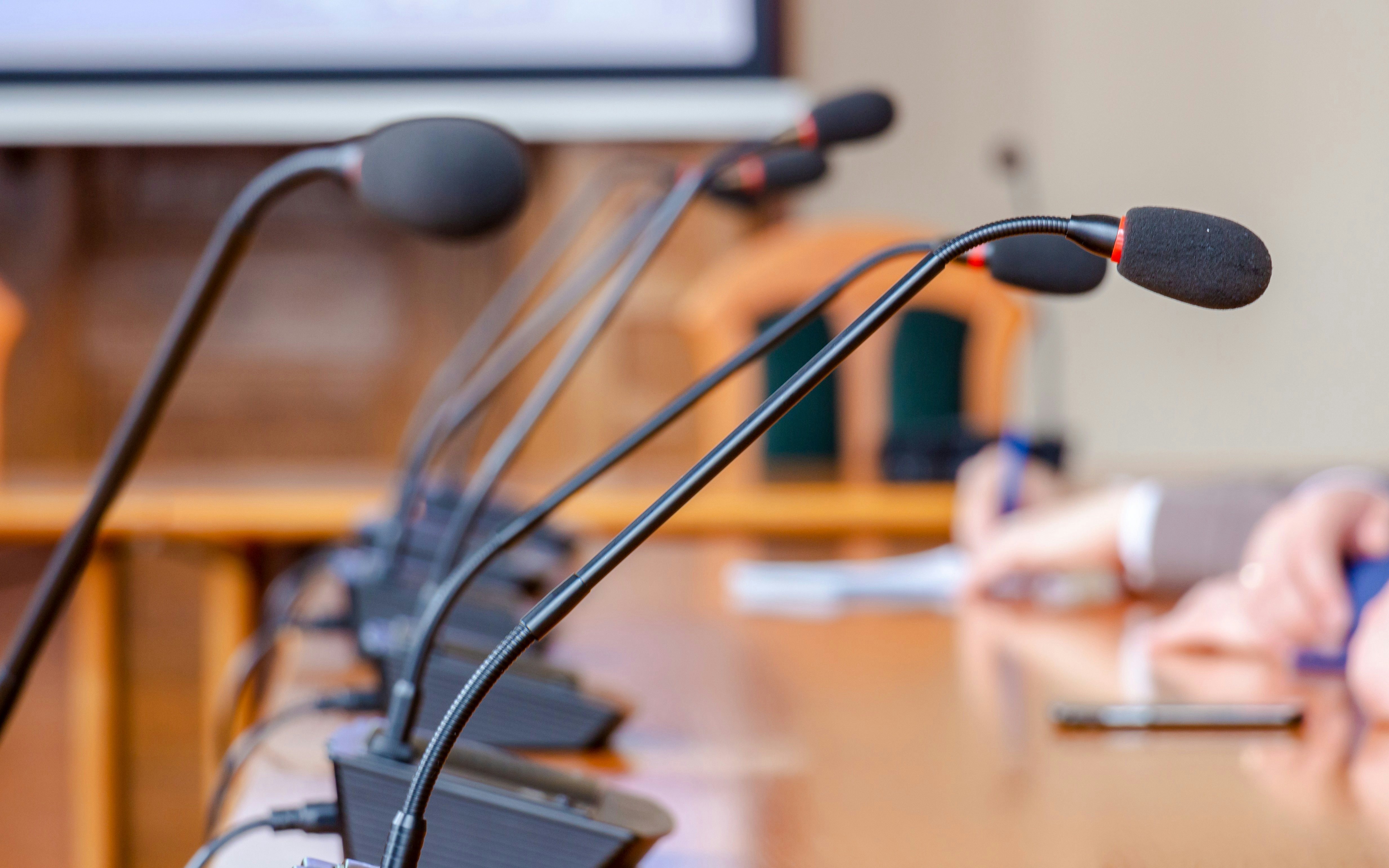 Press conference microphones on a wooden table.