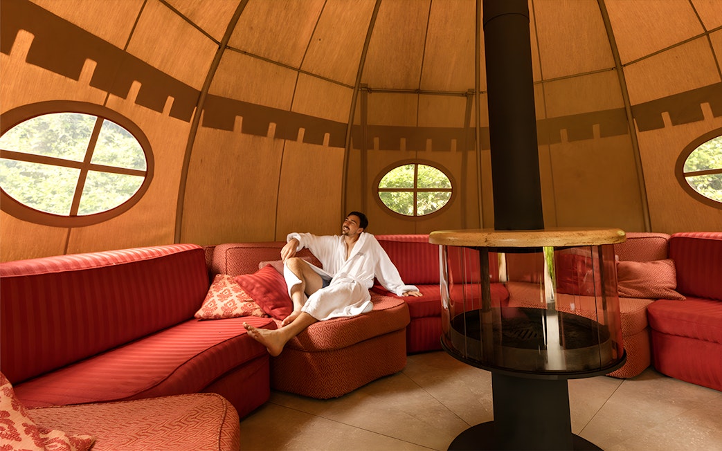 Man relaxing in a robe inside a cozy lounge at QC Terme Roma.
