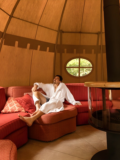 Man relaxing in a robe inside a cozy lounge at QC Terme Roma.
