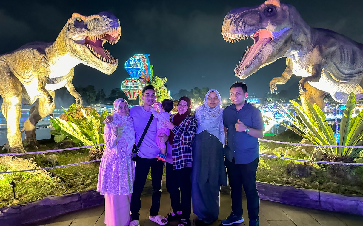 Group posing with dinosaur statues at night in 99 Wonderland Park.